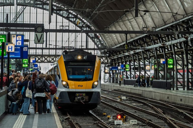 Navetiști care așteaptă trenul pe peron dimineața devreme