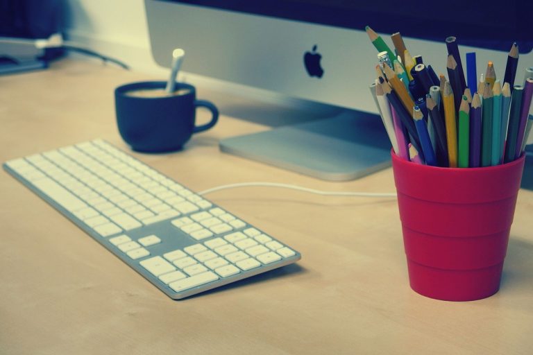 Doi oameni citesc împreună un contract tipărit, la un birou cu laptop și cafea